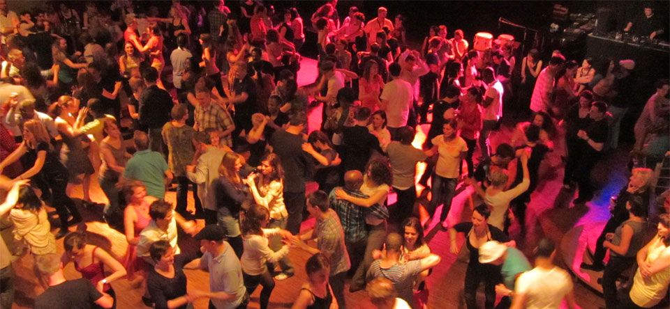 Couples dancing salsa together on a busy floor.