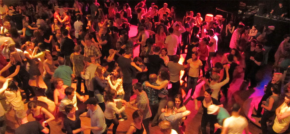 A packed salsa dance floor seen from above under red club lights.