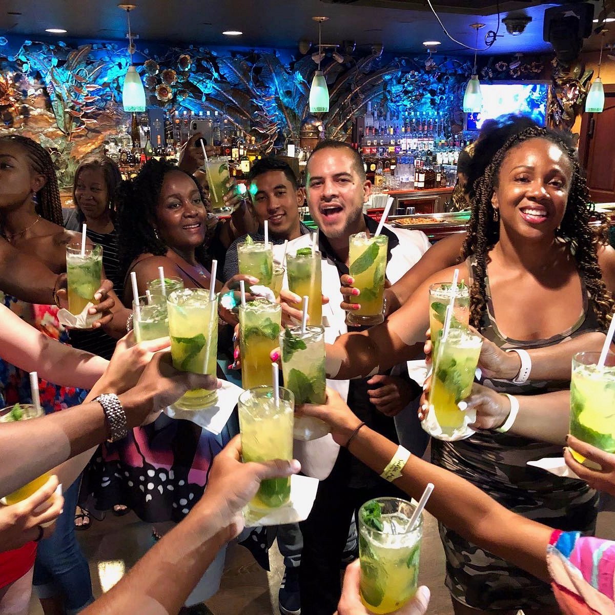 A group of salsa event guests raising cocktails together at the bar.