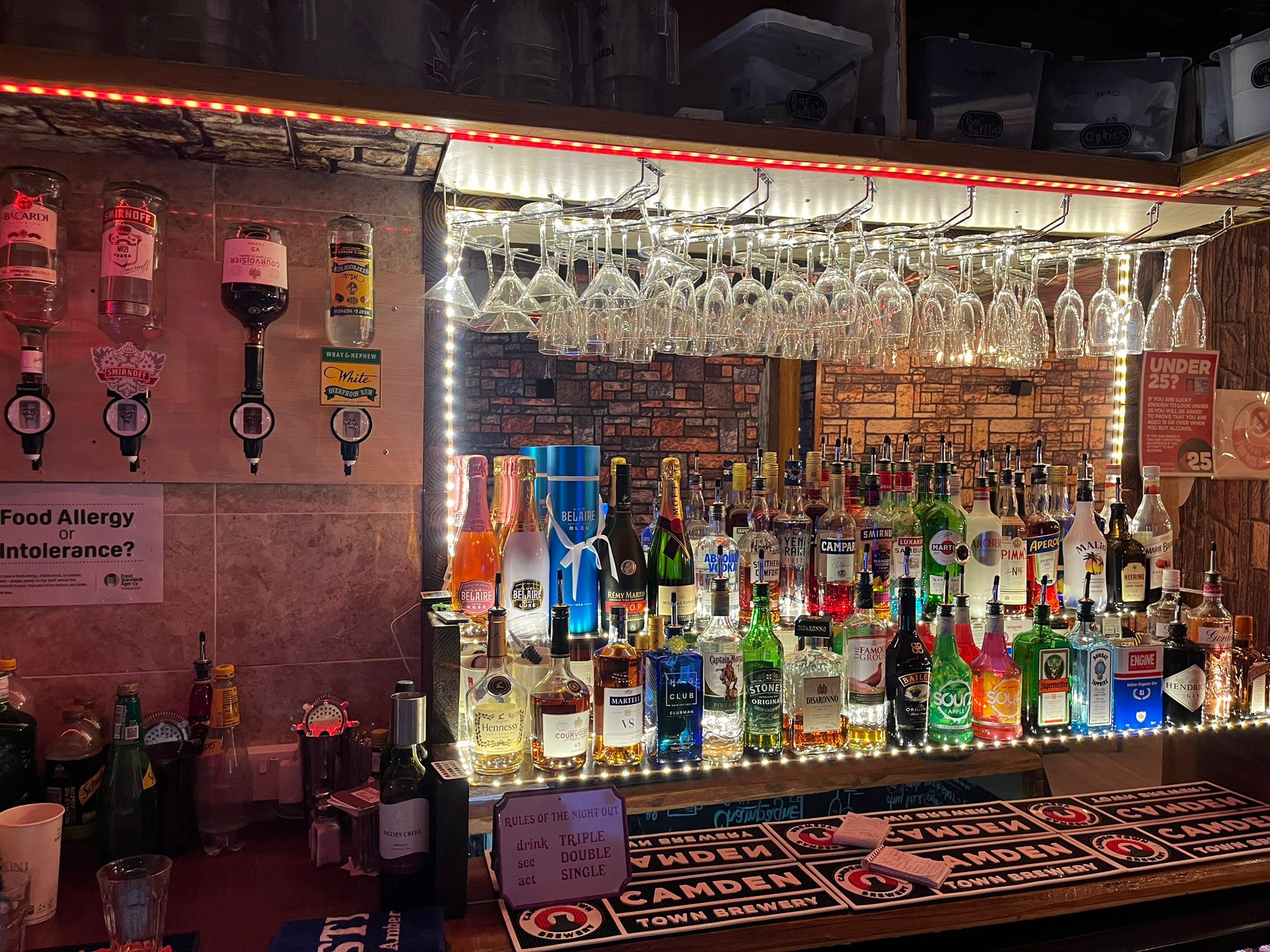 The Marmalade Club back bar, fully stocked and lit under neon.